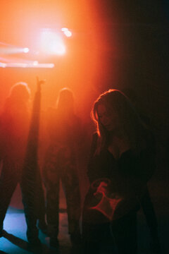Young woman dancing in dark with red spotlight at nightclub