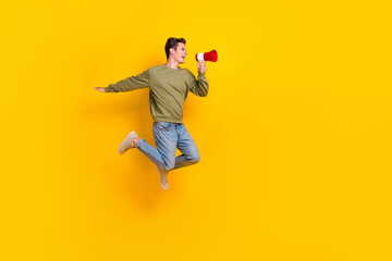 Fototapeta na wymiar Full size profile portrait of excited energetic man jump hold loudspeaker shout speak empty space isolated on yellow color background
