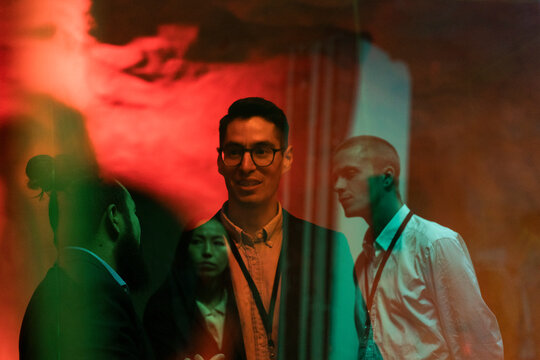Multiracial male and female colleagues planning strategy during meeting in illuminated workshop