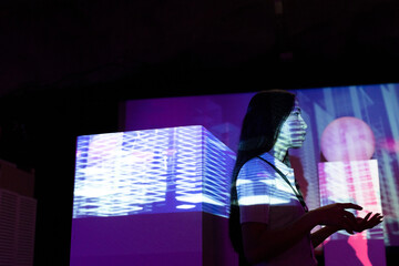 Side view of businesswoman gesturing by projection screen in illuminated convention center