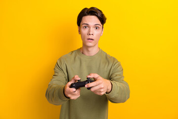 Portrait of focused young person arms hold controller play video games isolated on yellow color...