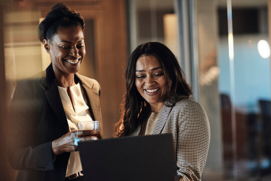 Happy business colleagues working on laptop at office