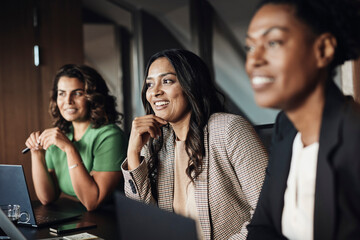 Smiling mature businesswoman with hand on chin planning strategy with colleagues at office