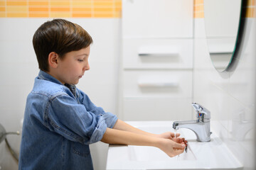 Child turns on water faucet in a restroom