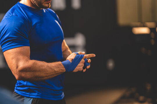 Closeup of hands of young male athlete trainer determined to workout for a healthy lifestyle tying band on hand for hand punch workout exercise in modern gym and fitness club