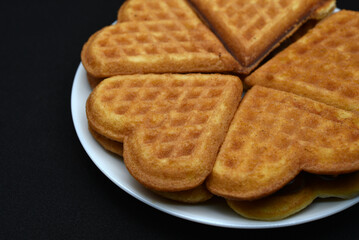 Heart-shaped waffles on a white plate. Delicious heart-shaped waffles.