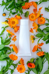 White plastic tube with face, hand and body cream and calendula,marigold flowers. Organic cosmetic concept, template. Flat lay,copy space. - obrazy, fototapety, plakaty