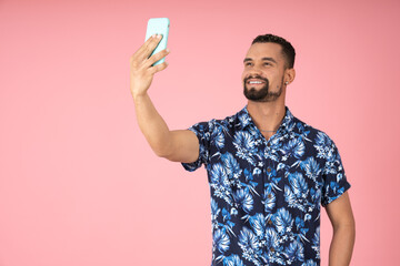 Man smiles as he takes a selfie with his cell phone