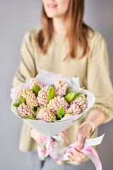  Florist woman creates beautiful bouquet of bouquets of spring pink hyacinths. European floral shop concept. Handsome fresh bunch. Education, master class and floristry courses. Flowers delivery.