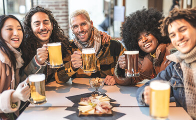 A group of multiracial friends raise their beer mugs in celebration at a pub event. Friends coming together and enjoying a night out.
