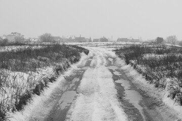 Road near the village in winter thaw