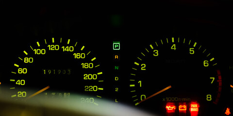 Classic analog illuminate car dashboard show speedometer and engine tachometer on blackk background.