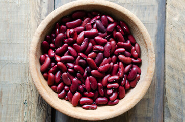 Red beans in a wooden bowl on a natural background. The concept of vegan food. Rustic style. Horizontal orientation. Top view