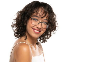 Young dark skinned smiling woman with makeup, glasses  and wavy hair posing on a white background