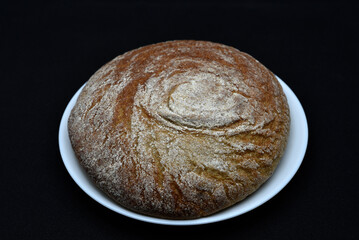 A loaf of black rye bread on a plate. Delicious black bread.