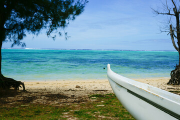 Outrigger canoe on beach between trees