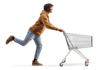 Full length profile shot of a young african american man running with an empty shopping cart