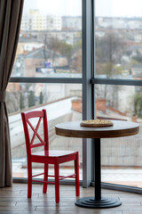 Pizza on a wooden board stands on a table near a window in a cafe