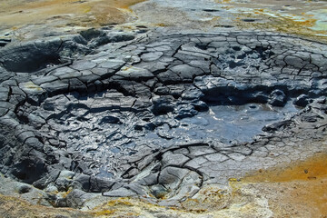 Closeup of grey hot thermal bubbling water mud pot hole in cracked fissured ground - Seltun Krysuvik Iceland