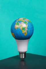 Light bulb with Earth planet model with space for text. Global ecology, International Day of Energy Saving or Earth Hour concept. On a turquoise background.