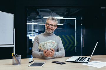 Portrait of mature and successful banker financier, senior businessman smiling and looking at...
