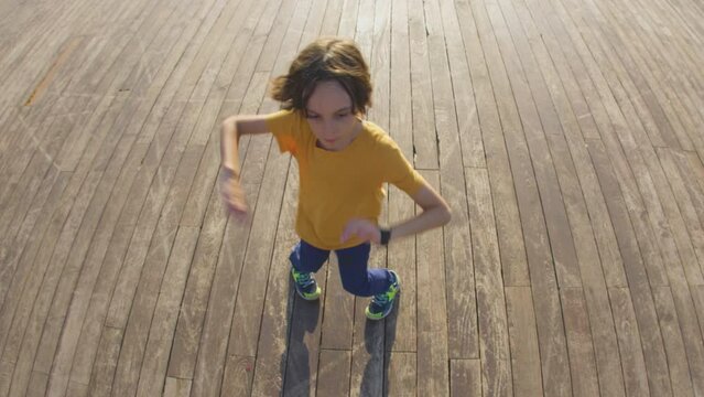 dancing boy. dances break-dance on the street, rhythmically waving his arms. hip hop dancer, boy practicing dance exercises, doing freestyle moves in the city
