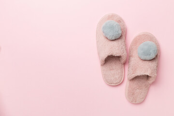 Soft pink slippers on color background, top view