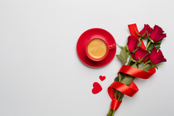 Red cup of coffee with roses on color background, top view