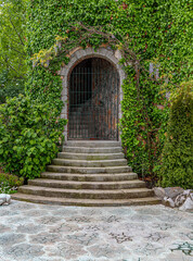 Fototapeta na wymiar Stone steps and entrance to an arched building overgrown with ivy.