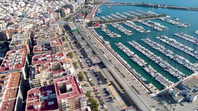 Aerial view of costal city Santa Pola. Situated in southeast of Spain Valencian Community is a famous travel destination. View of beautiful marina of Santa Pola. Baots docked. Descending and tilt up
