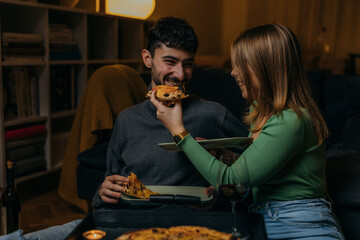 Woman feeding her boyfriend with pizza