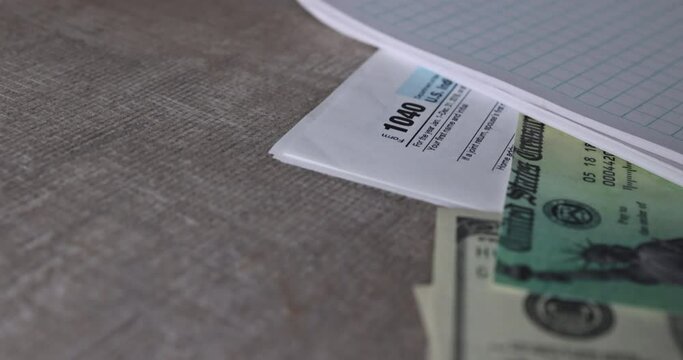 On desk 1040 individual income tax form, pen calculator, and dollar bills, tax return stimulus check