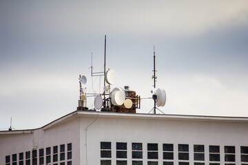 Cellular signal receiving stations and satellite dishes on the roof of a high-rise residential...