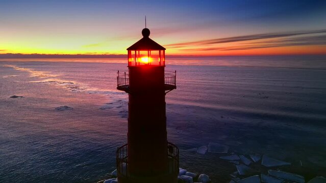 The splendid beauty of a lighthouse amid morning twilight in Winter, reflected in an ice covered harbor on Lake Michigan. So cold and so very colorful.