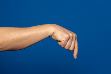 Strong hand of man pointing index finger down isolated on blue background.