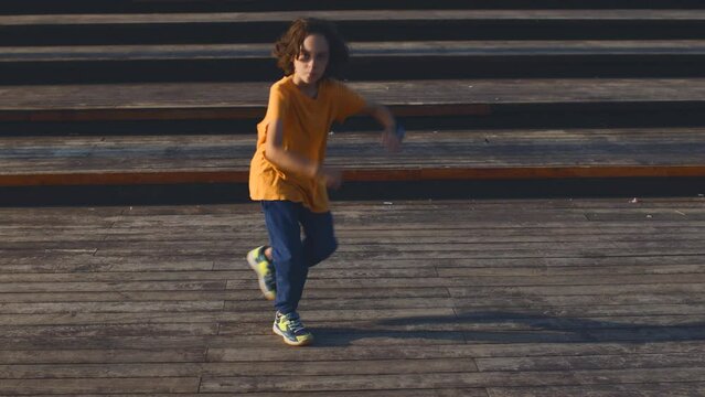 dancing boy. dances break-dance on the street, rhythmically waving his arms. hip hop dancer, boy practicing dance exercises, doing freestyle moves in the city