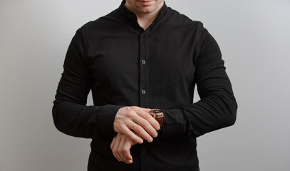 Unrecognizable man in black shirt checking time on his wrist watch, grey background - 569311014