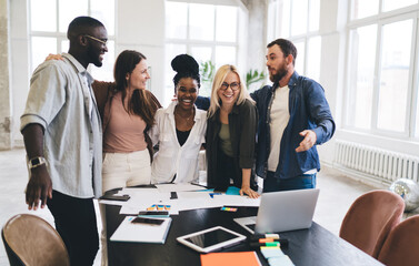 Young diverse architects hugging and having fun in workshop