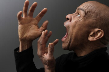 man screaming and shouting with anger on grey background with people stock photo	 