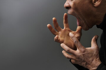 man screaming and shouting with anger on grey background with people stock photo	 