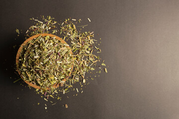 Catnip herb in latin - Nepeta cataria in a wooden bowl on a black background. Medicinal herb.  Flat...