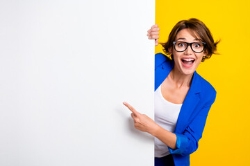 Photo of impressed funky lady dressed blue blazer eyewear pointing white wall placard empty space...
