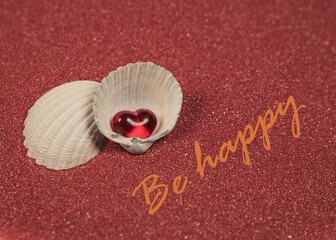 czerwone serce w muszelce na czerwonym piasku na szczęście © siwyk