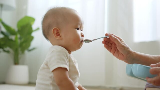 Asian baby refuse, reject to eat food while mother feeding