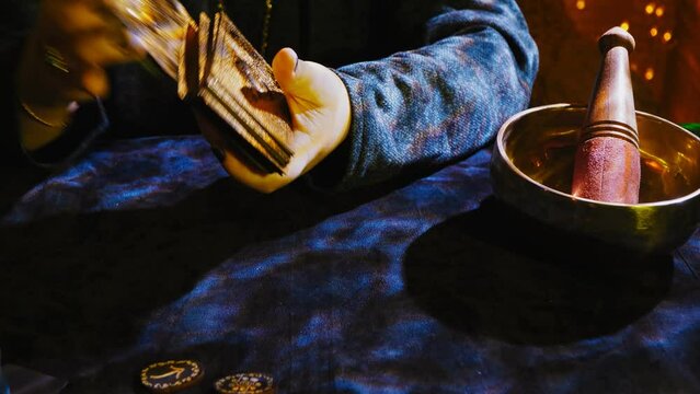 A fortune-teller reads tarot cards on a dark velvet table by candlelight in the twilight. Medium plan.