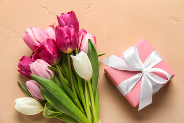 Gift box and bouquet of beautiful tulip flowers on color background