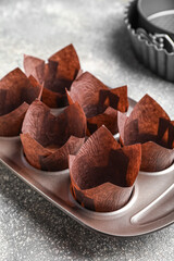 Tray with paper molds for muffins on light background, closeup