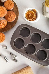 Tray, tasty muffins and piping tips on light background