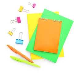 Colorful notebooks, paper clips and pens on white background