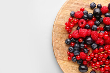 Wooden board of fresh berries on color background, closeup